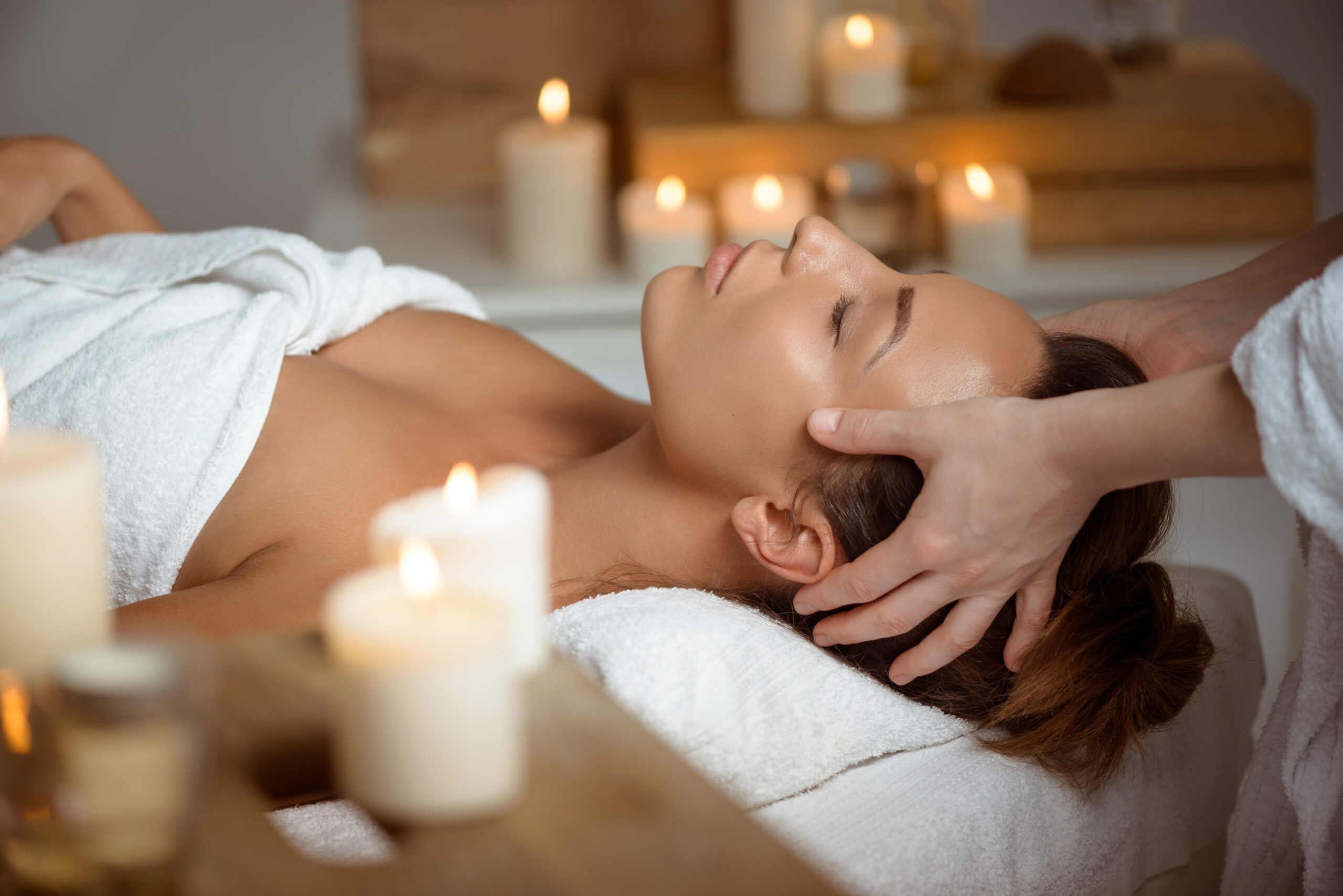 Young beautiful girl having face massage relaxing in spa salon. Young beautiful brunette girl having face massage relaxing in spa salon. Eyes closed. Copy space.